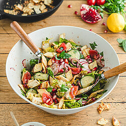 Frischer Fattoush-Brotsalat mit Sumak-Dressing und knusprigem Fladenbrot angerichtet in einer weißen Schüssel. Ein libanesisches Rezept für den Sommer.