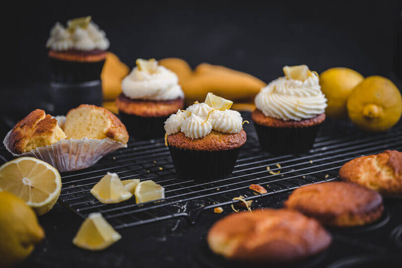 Saftige Joghurt-Zitronen-Muffins mit Zitronenfrosting auf einem Kuchengitter