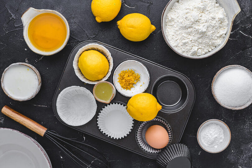 Alle Zutaten für das Zitronenmuffin-Rezept: frische Zitronen, Mehl, Eier, Zucker, Öl und Joghurt