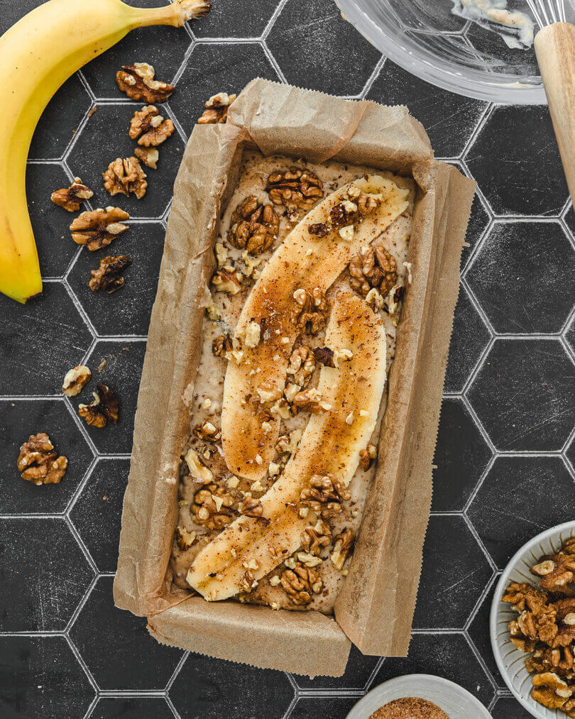 Bananenbrot Teig mit Topping aus Bananen, braunem Zucker und Walnüssen in einer Kastenform